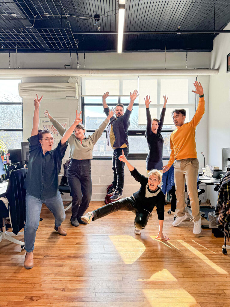 Estelle, Jessie, Mathieu, Marie-Blanche, Julian and Celia jump for joy, arms in the air. The photo was taken by Francis in our office, brightly lit by the sun.